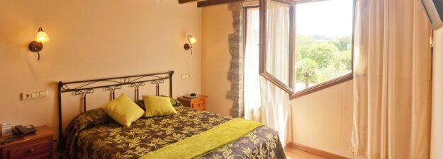 habitación doble estilo moderno donde se ve la cama y vistas de la naturaleza a través de la ventana